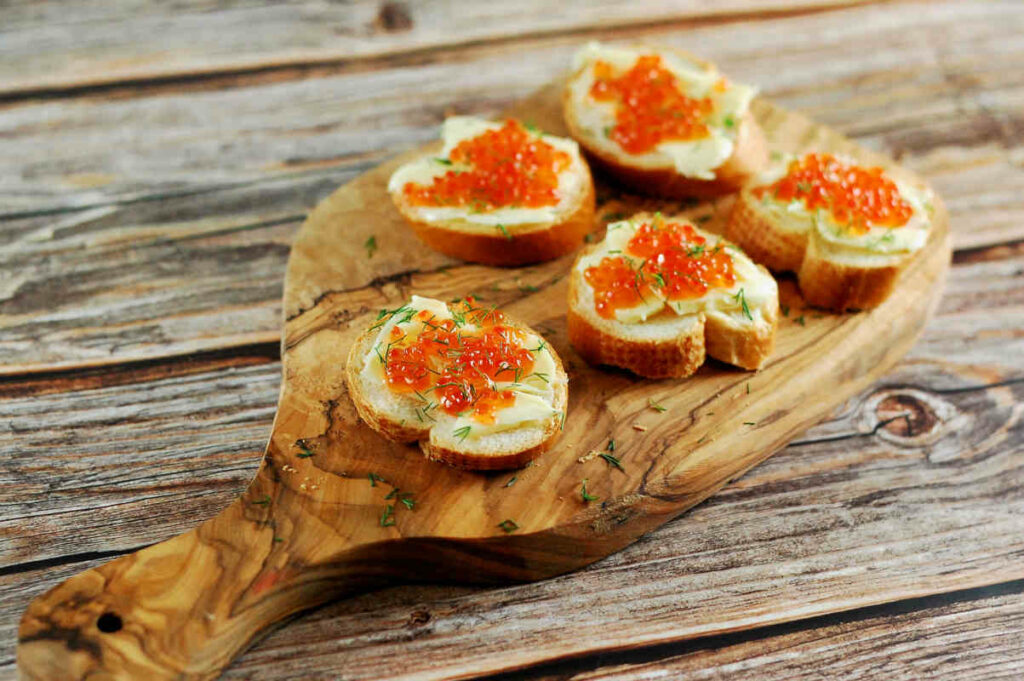 tagliere di legno con tartine al caviale e vodka