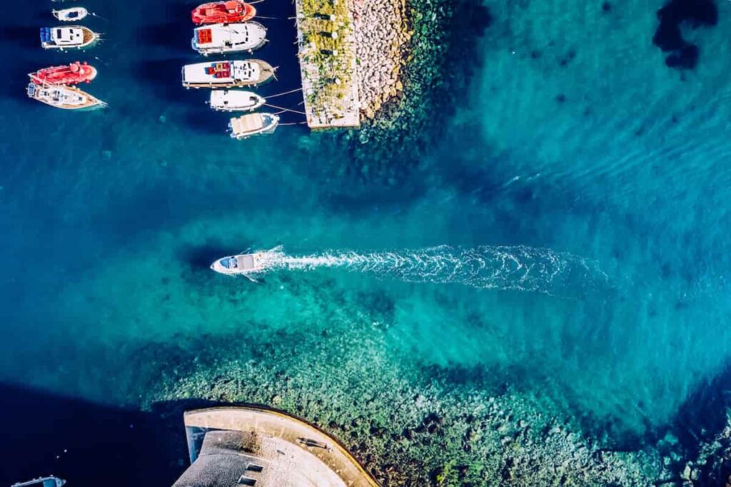 mare cristallino visto dall'alto con barche in lontananza 