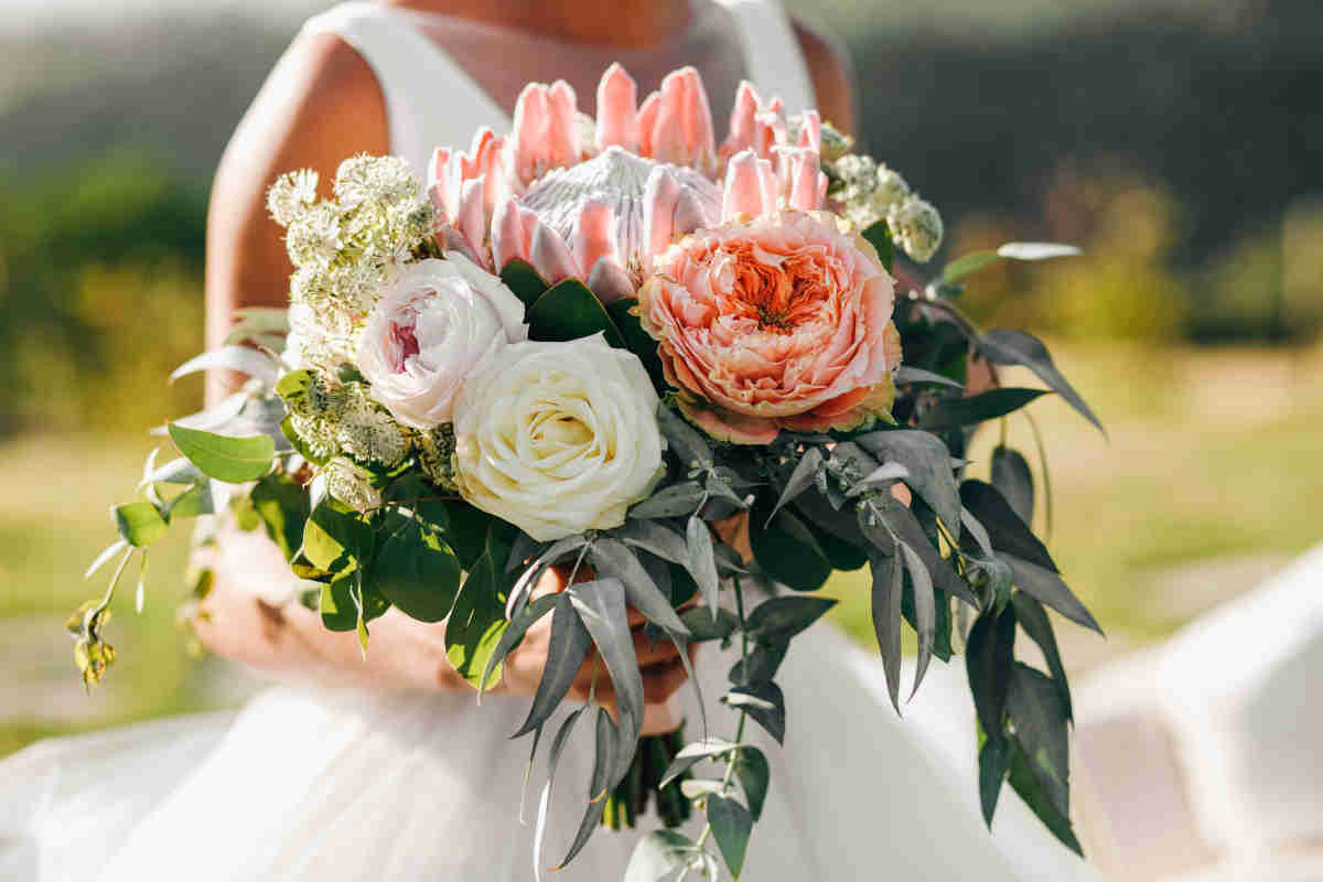 Sposa in abito bianco con mazzo di fiori fra le mani