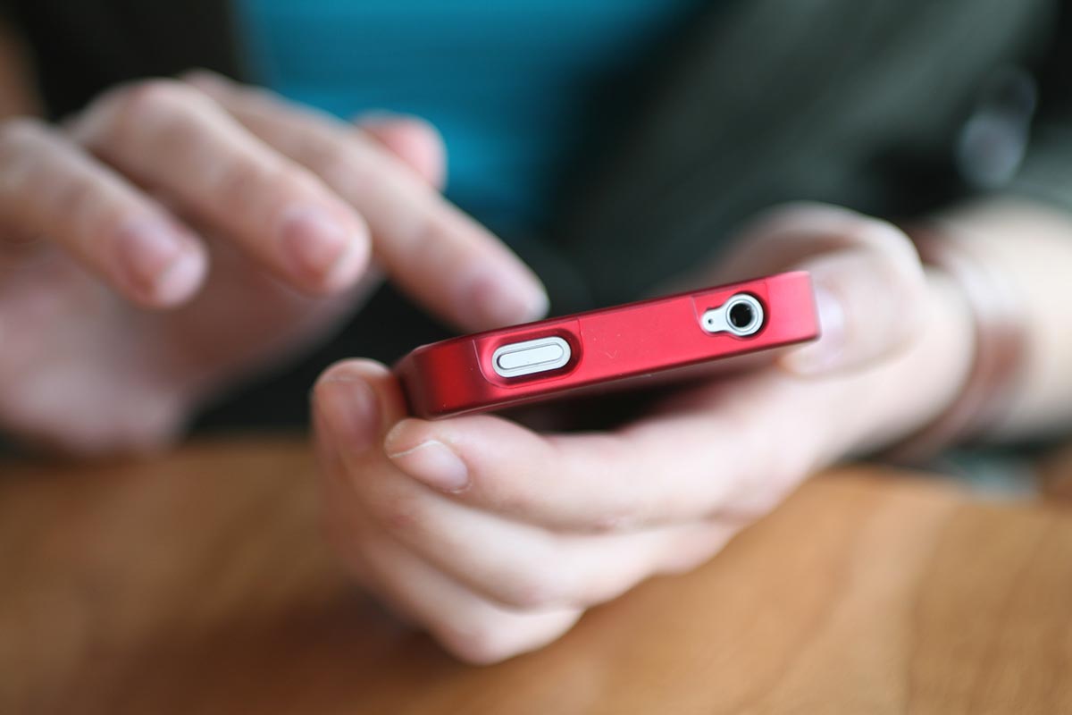 Ragazza che ha fra le mani un telefono cellulare di colore rosso