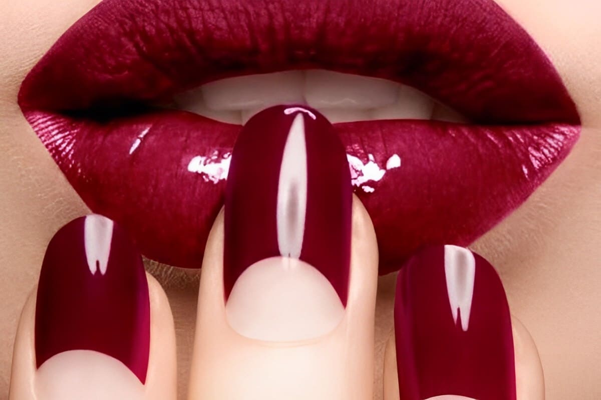 Scatto Half Moon Manicure in bordeaux abbinato a rossetto laccato dello stesso colore