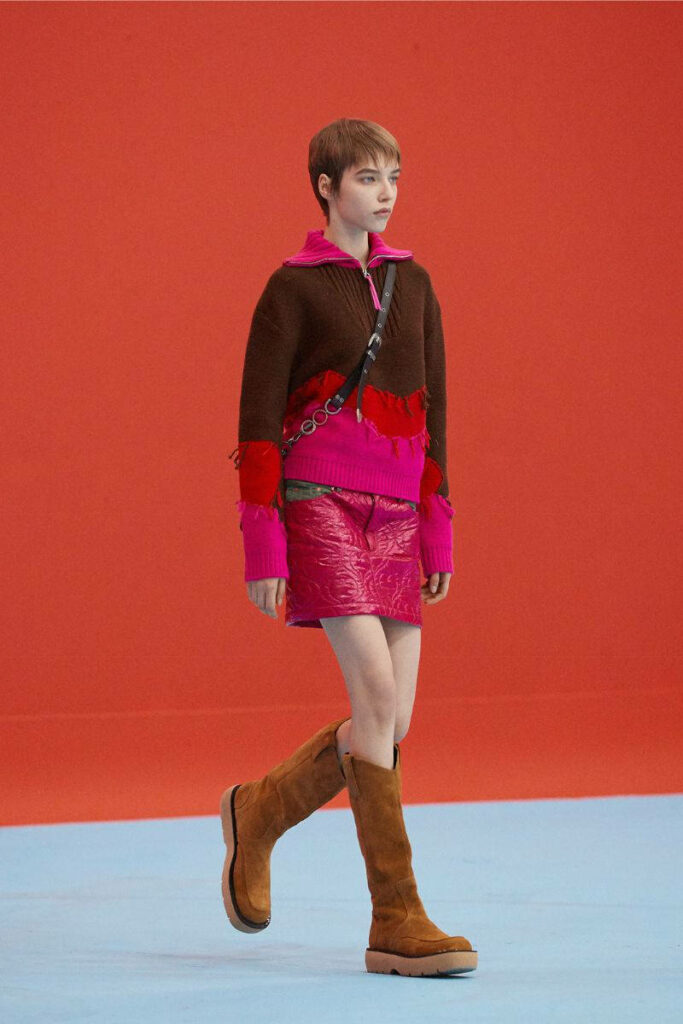 donna con minigonna, boots e maglione con zip marrone e rosa