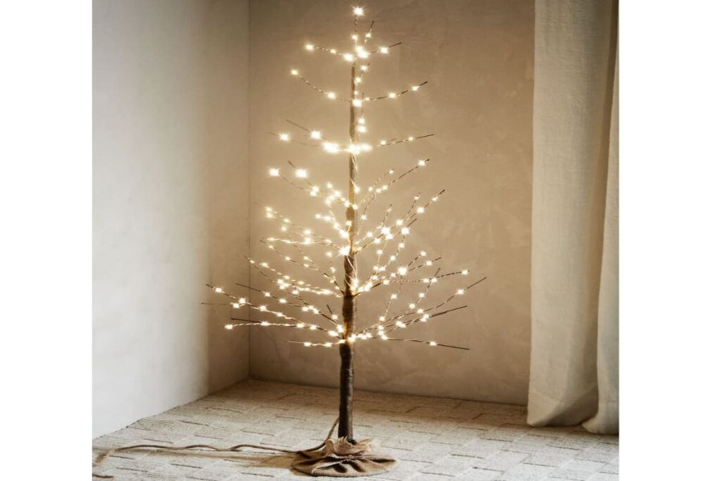 albero di natale con luci a led, privo di foglie, in un soggiorno dai colori neutro