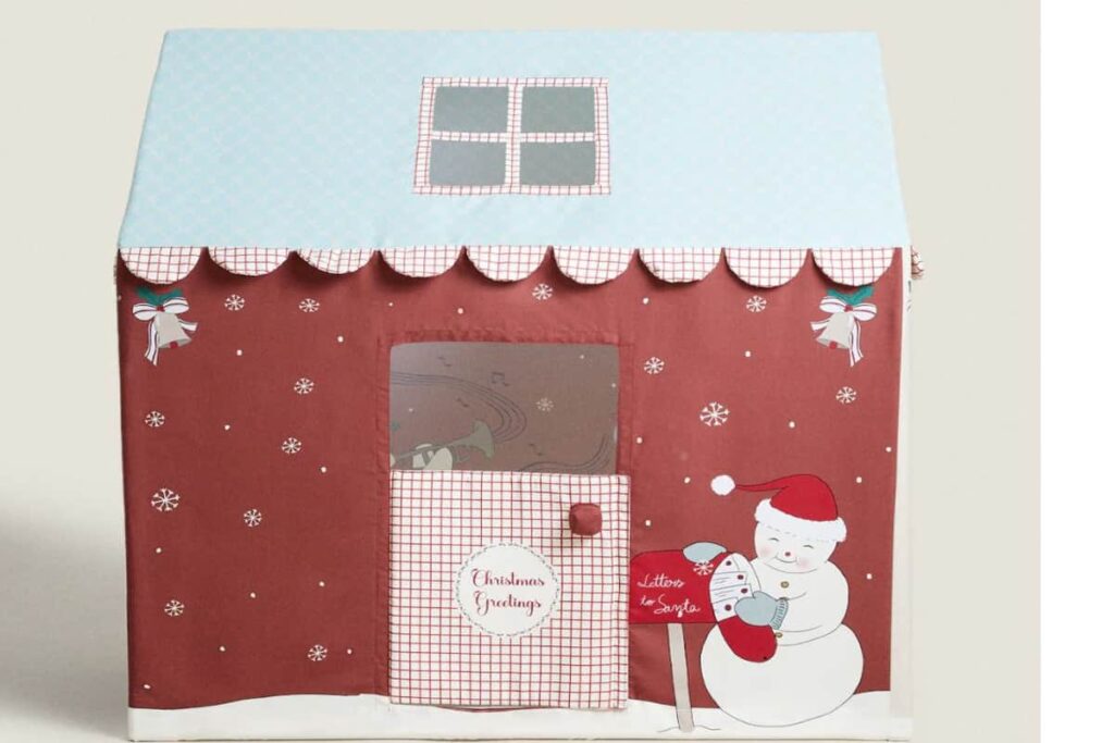 casetta giocattolo per bambini a tema natalizio , con il tetto celeste e il resto della casa color mattone, con un pupazzo di neve disegnato