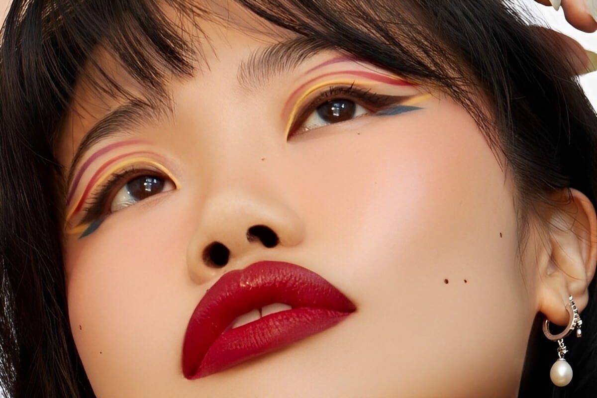 primo piano viso modella con rossetto rosso e make-up occhi grafico