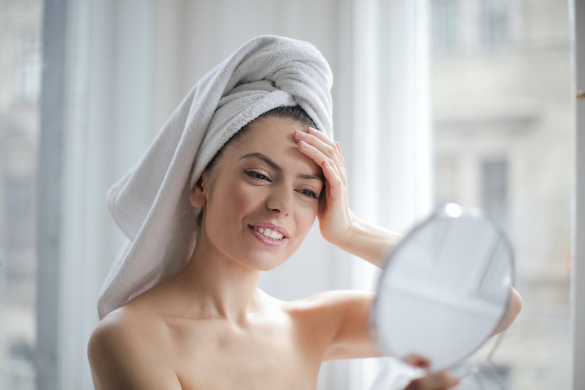 Ragazza con asciugamano in testa che si guarda allo specchio
