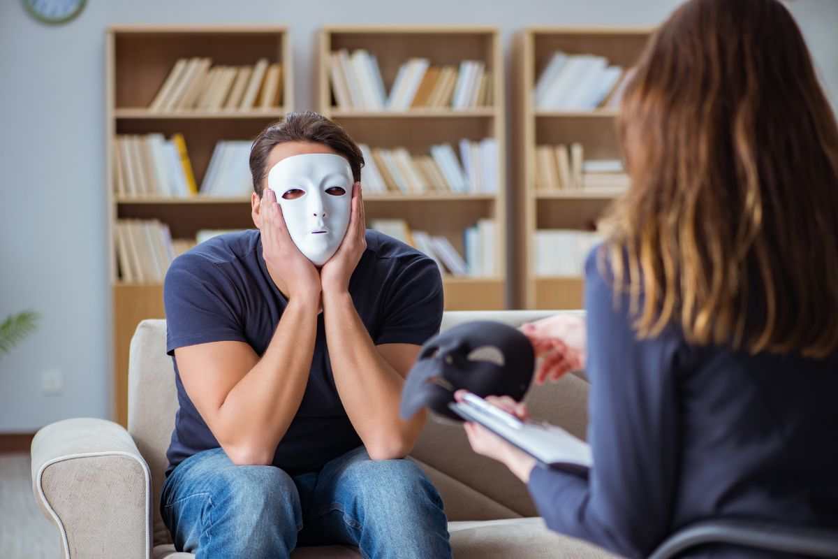 persona con maschera sul viso seduta sul divano di fronte ad un'altra persona