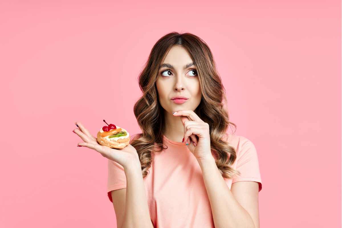 ragazza dubbiosa con dolcetto alla frutta in mano