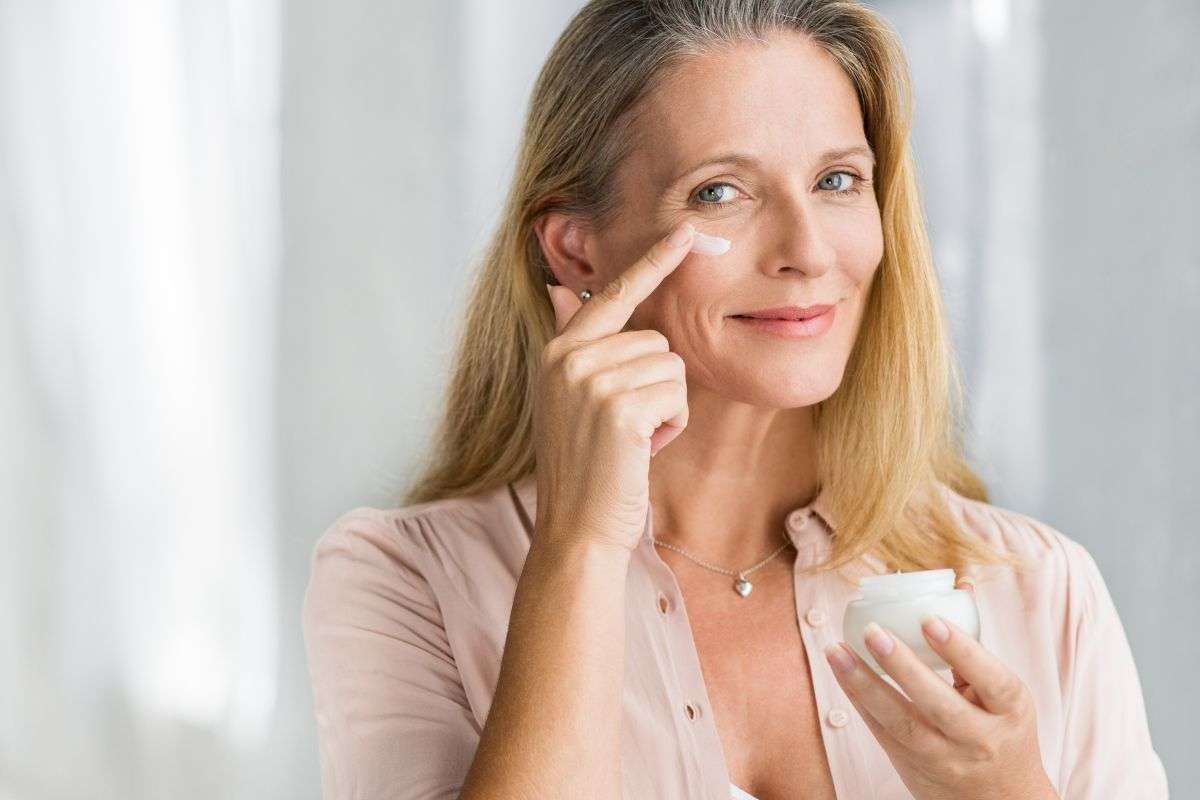 Donna non giovanissima che applica crema sul viso