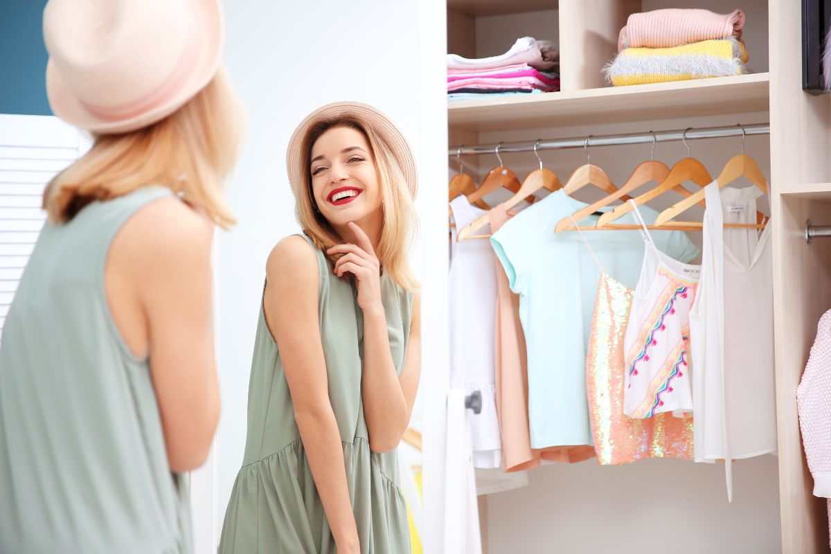 ragazza sorridente davanti lo specchio e il guardaroba aperto