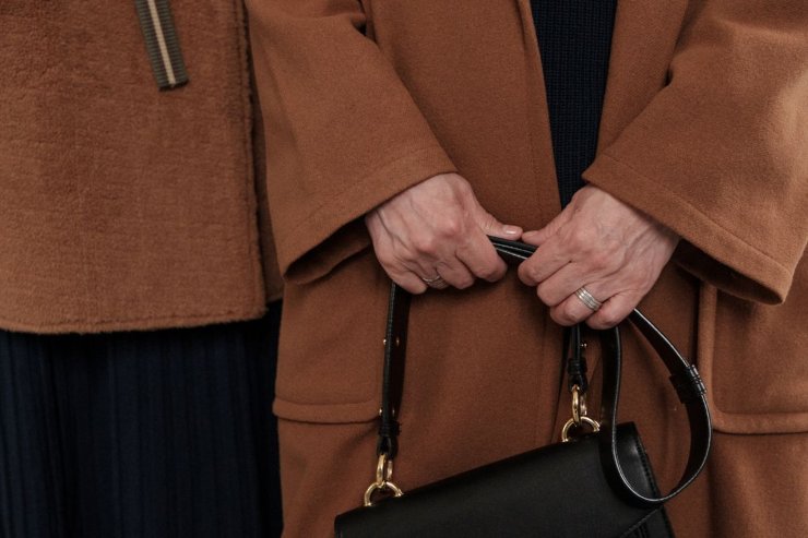 donne con cappotto marrone e borsa nera in mano