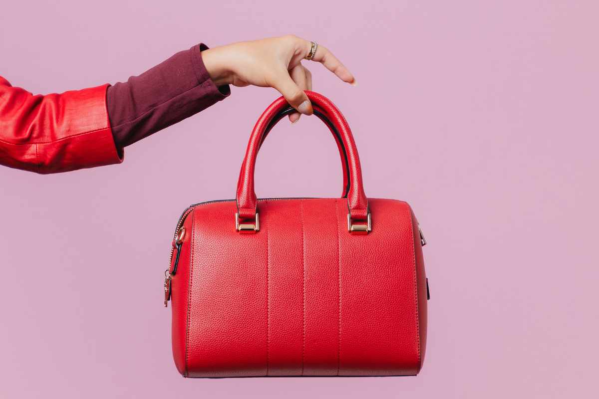 mano che tiene borsa rossa
