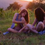 Ragazze sul prato al tramonto che si grattano per le punture di zanzare