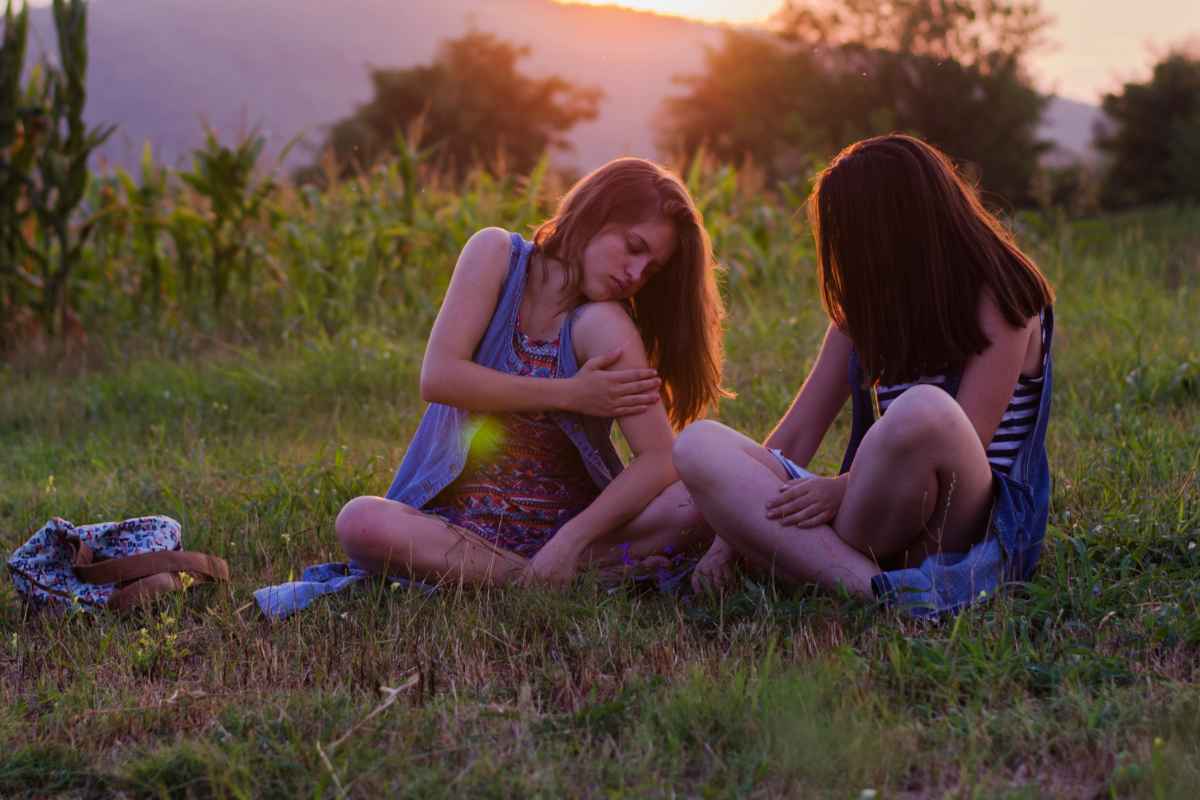 Ragazze sul prato al tramonto che si grattano per le punture di zanzare