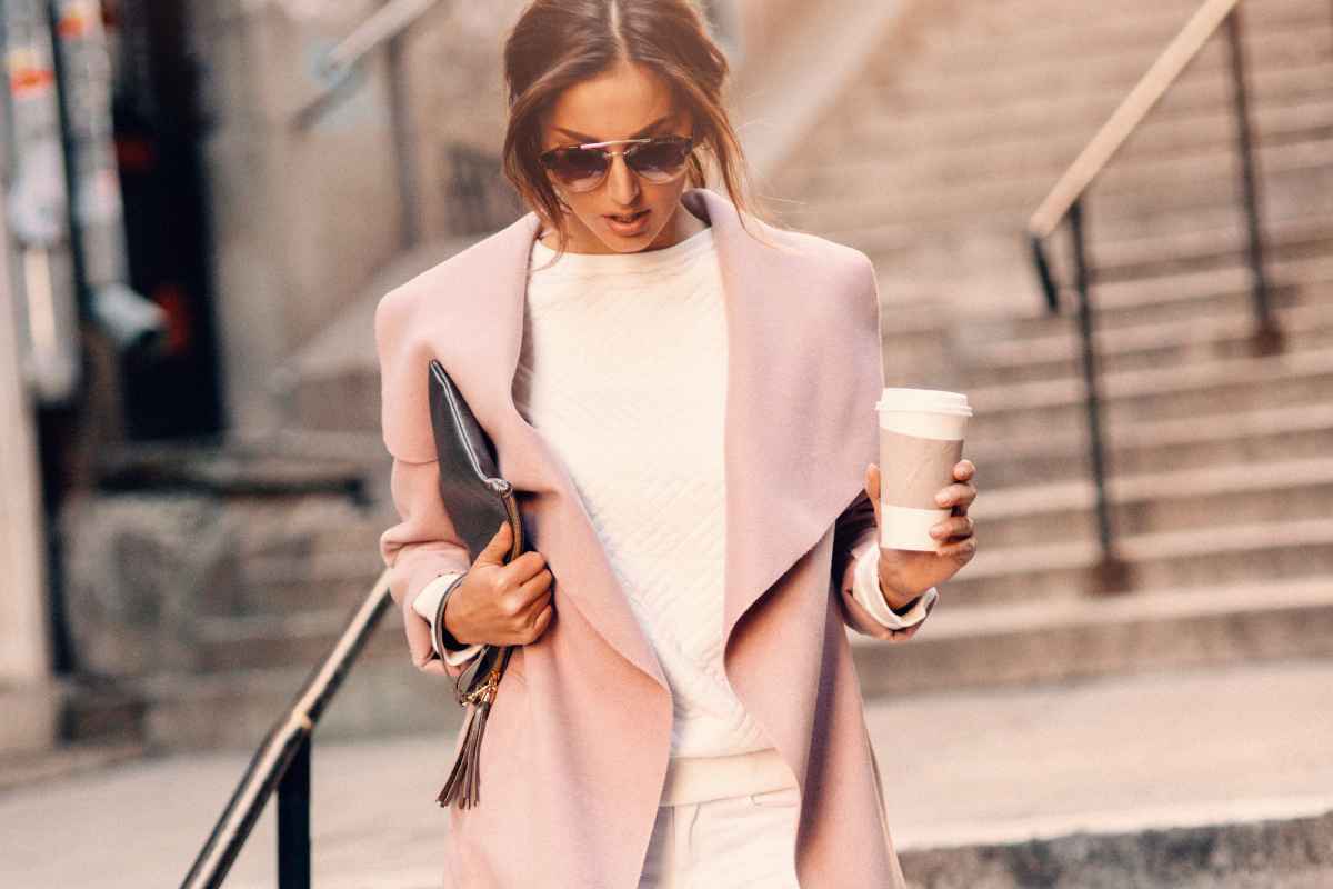 donna elegante con occhiali da sole, borsa a mano e bicchiere