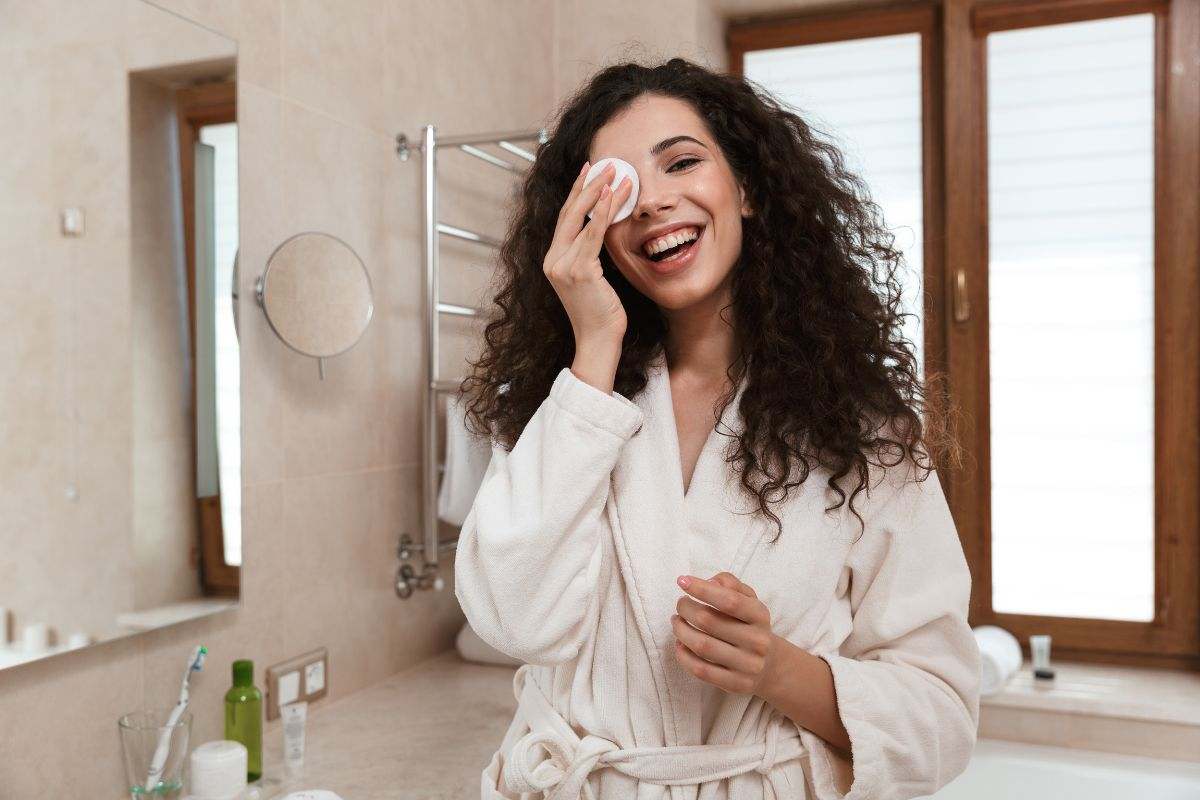 ragazza con accappatoio che si strucca in bagno