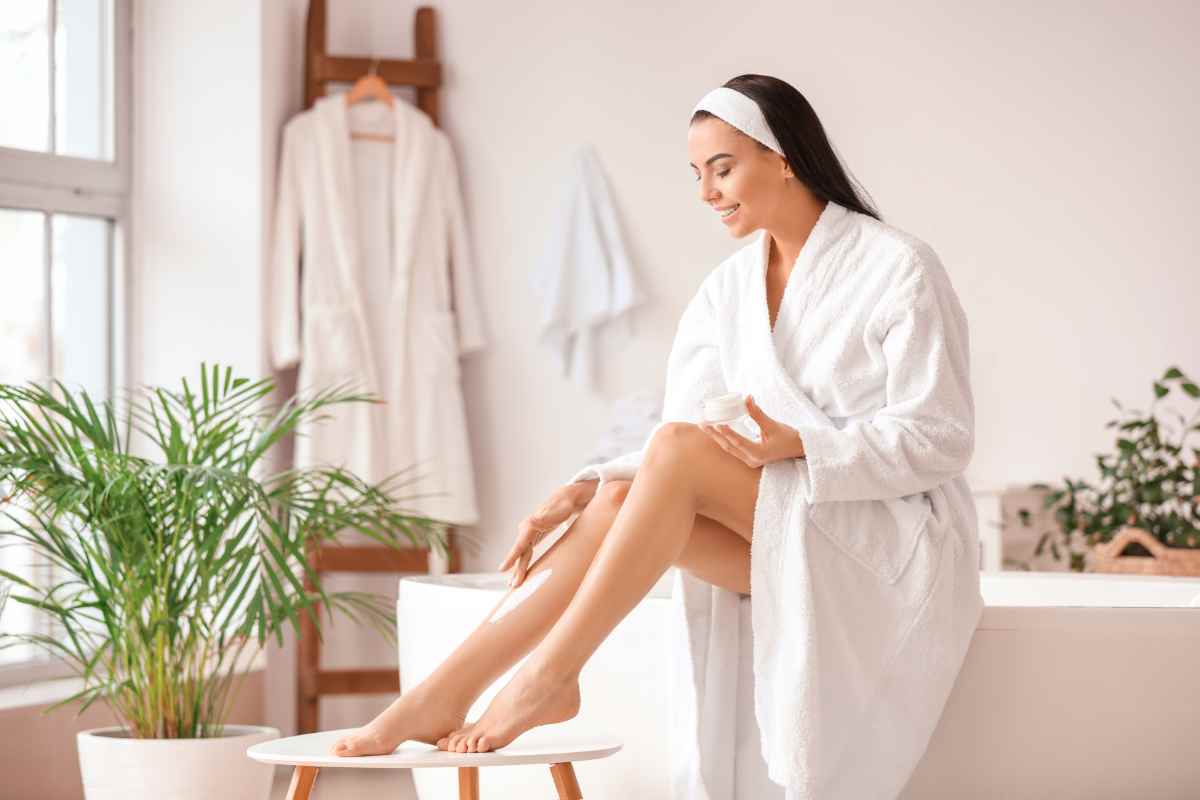 donna in bagno che mette crema idratante corpo