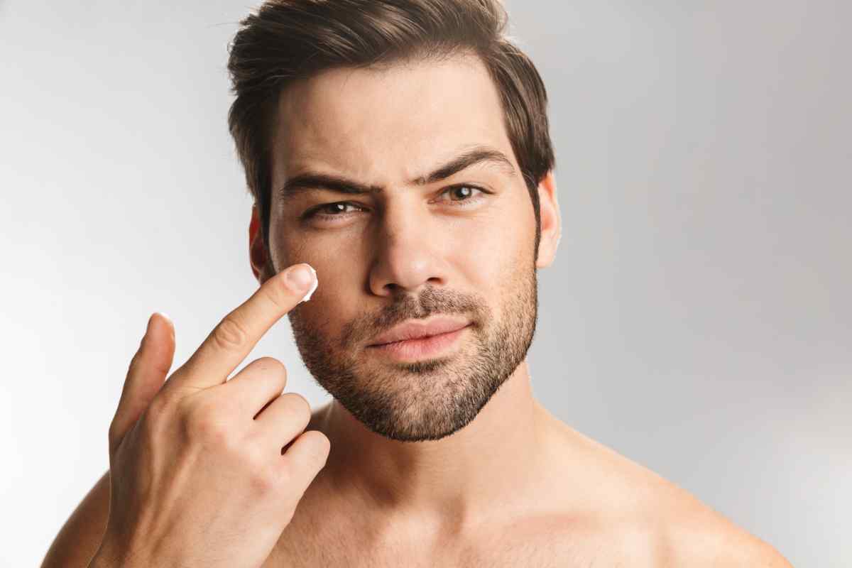 uomo che mette la crema sul viso