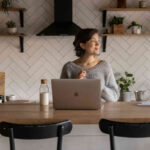Donna seduta al tavolo in cucina davanti a un laptop