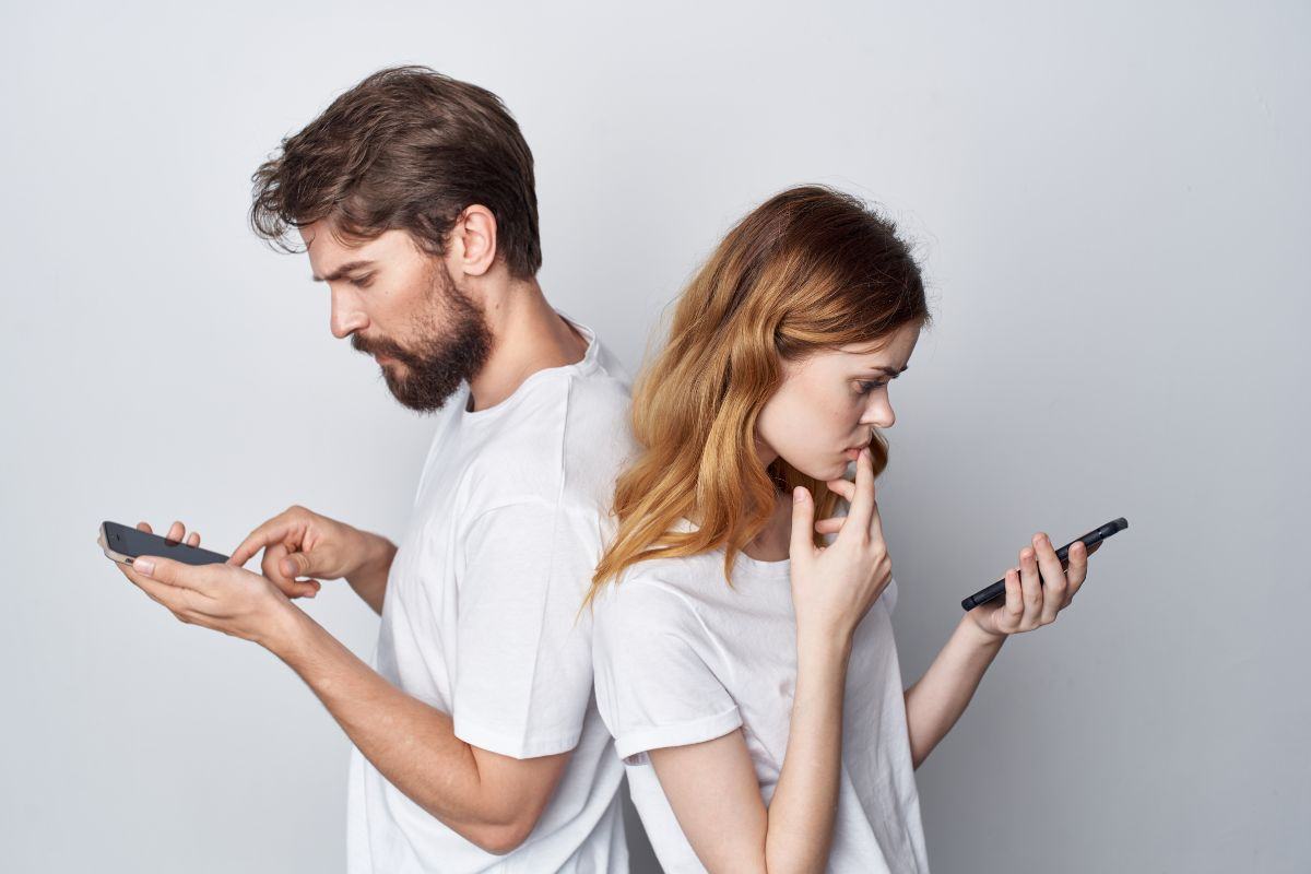 due persone poggiate di spalle con smartphone in mano