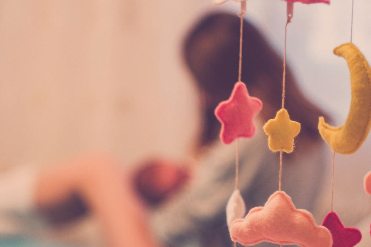 Mamma che culla un bebè, con in primo piano le stelline di una culla