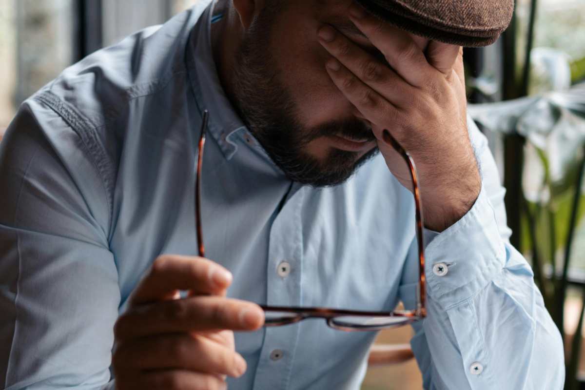 Uomo disperato che si copre gli occhi con una mano