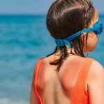 bambina di spalle al mare con scottatura sulla schiena