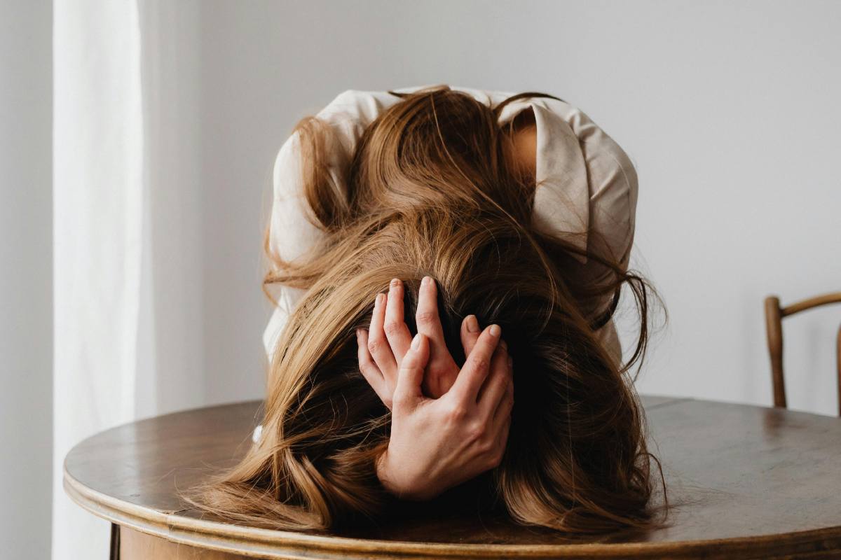 Ragazza che si tiene la testa, abbattuta su un tavolo