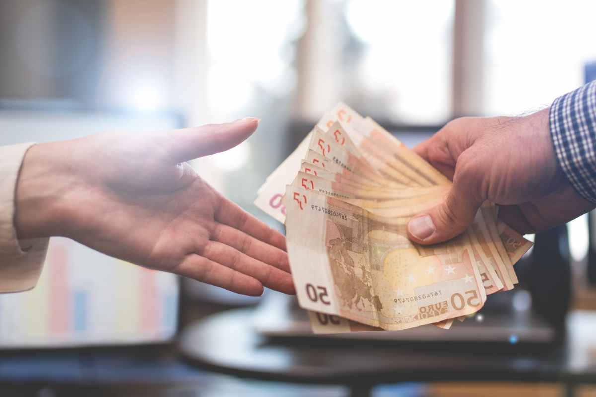 mani si passano delle banconote euro come simbolo dell'assegno di inclusione per i poveri