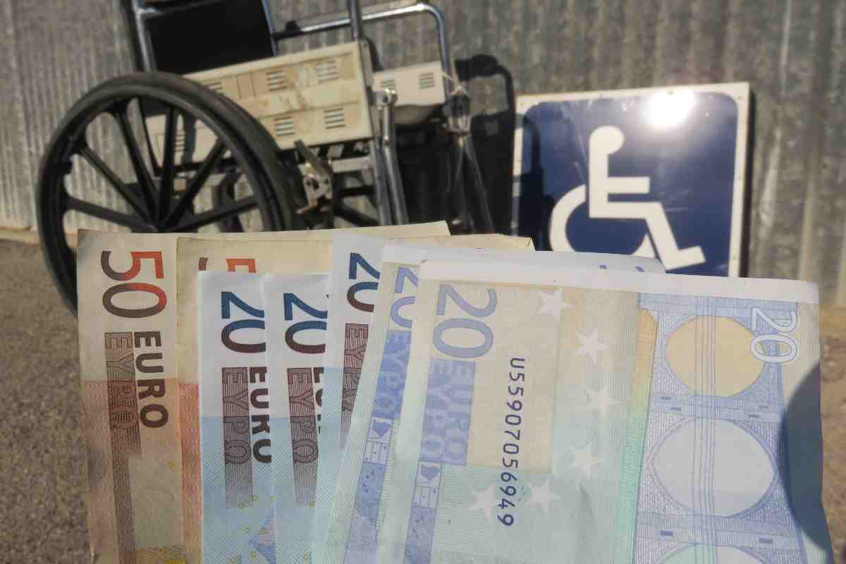 banconote e sedia a rotelle simbolo di come cambia l'assegno minimo per le pensioni di invalidità