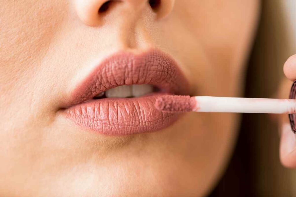 ragazza stende il rossetto in crema