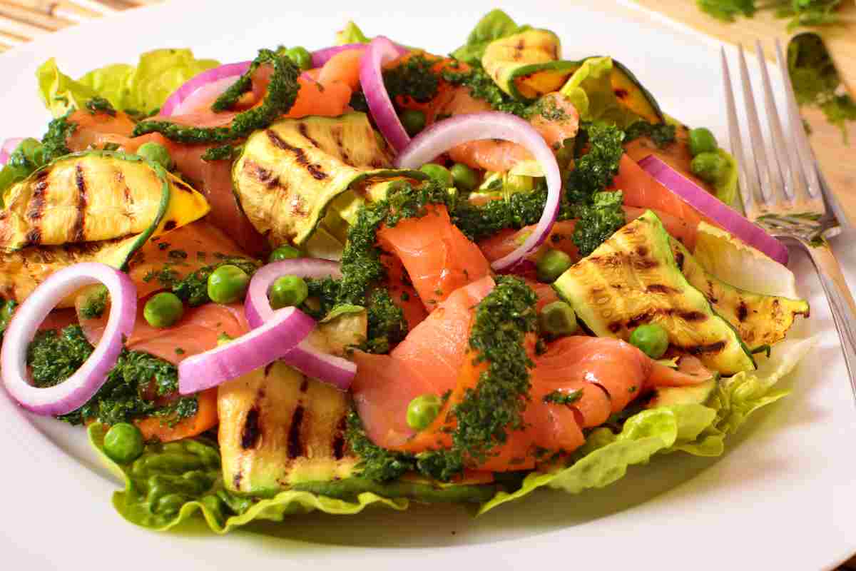 piatto di insalata con salmone affumicato, zucchine grigliate, piselli, pesto e cipolla