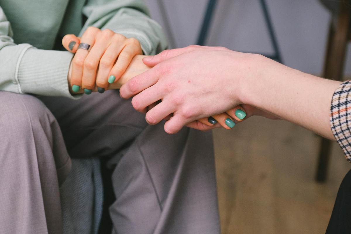 Delle mani fra le mani in un gesto di conforto