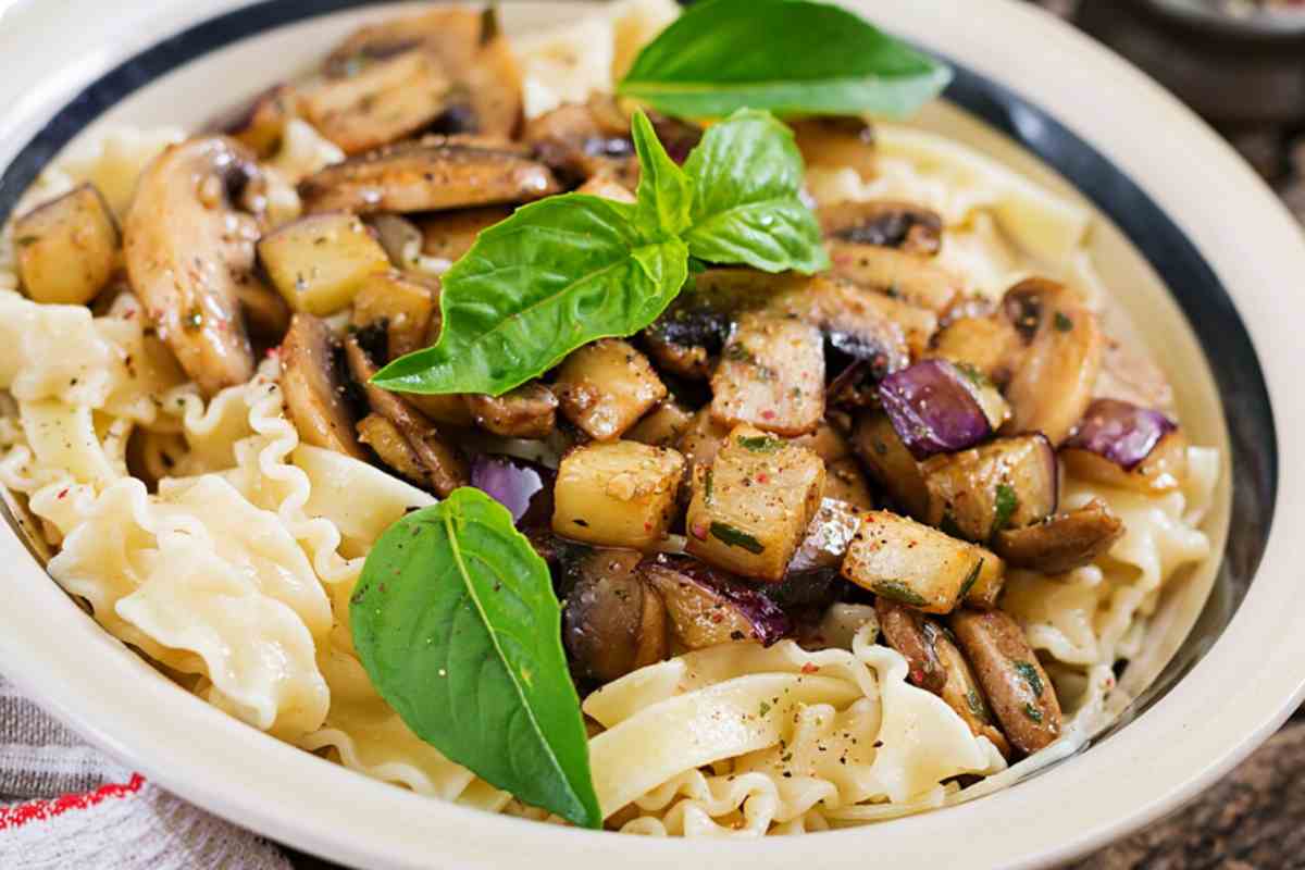 piatto con pasta alla Norma bianca con melanzane e ricotta salata guarnita con foglie di basilico