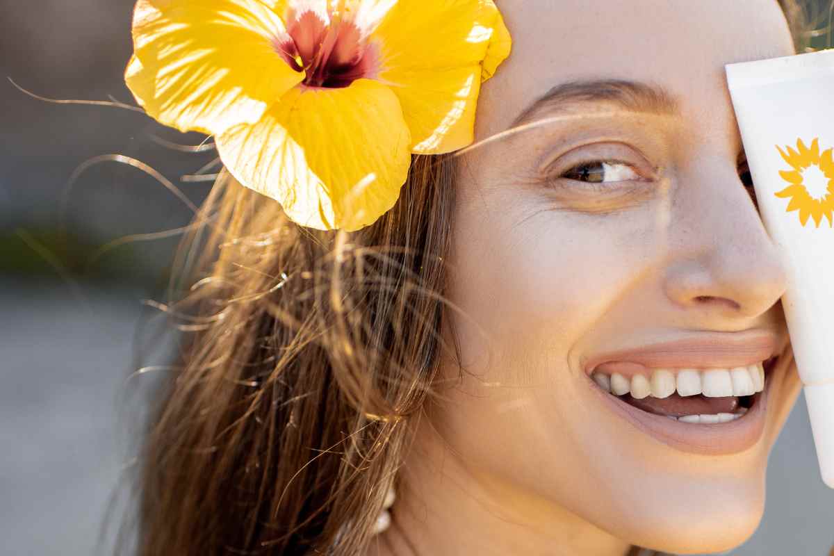 ragazza sorridente con protezione solare stick in mano