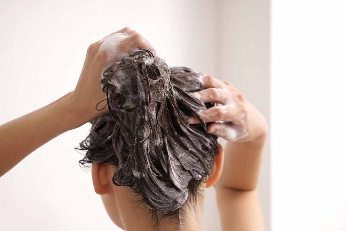 ragazza lava i capelli con lo scrub per il cuoio capelluto