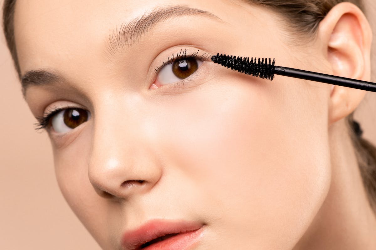 donna con pennellino mascara premuto sul volto