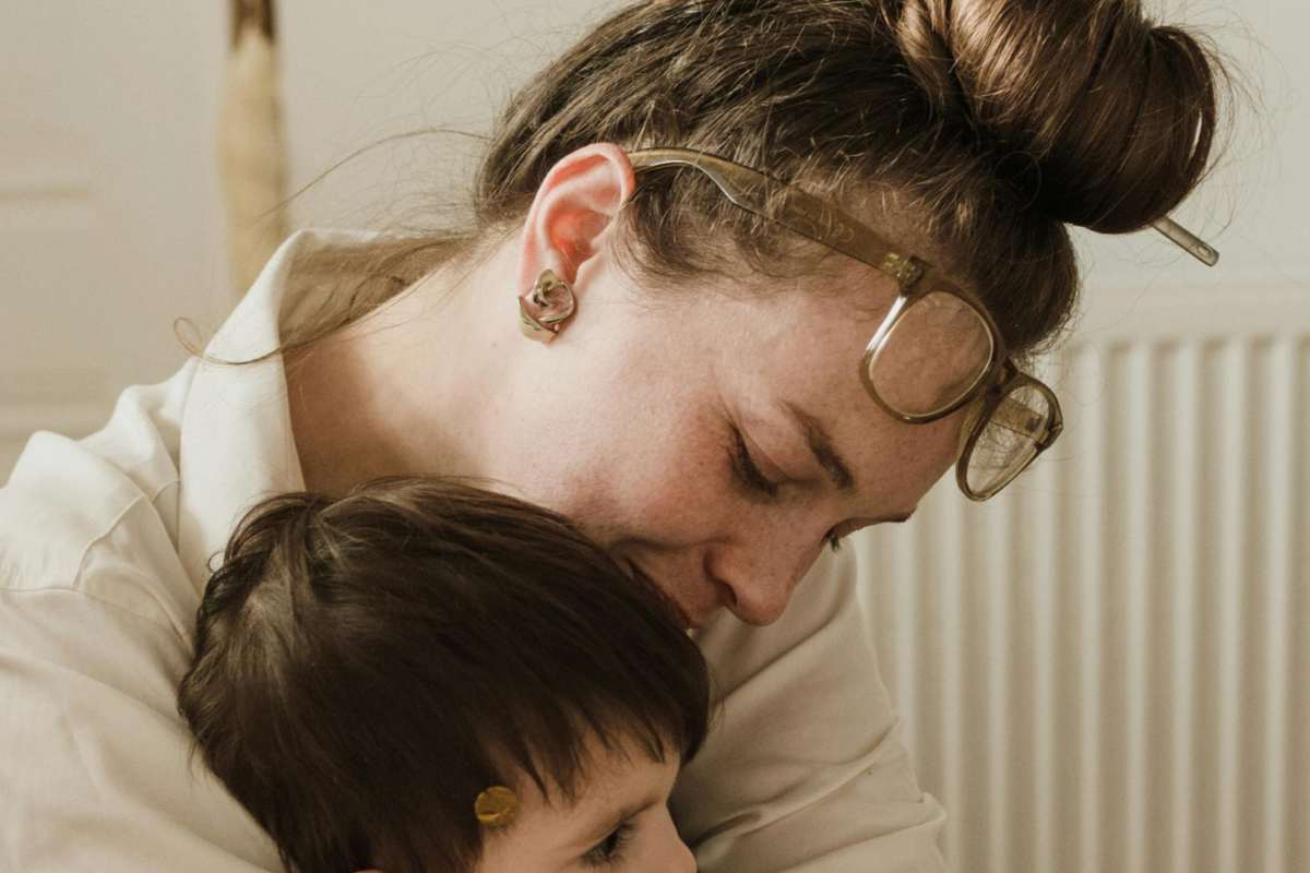 Una madre con i capelli raccolti che tiene in braccio un bimbo piccolo