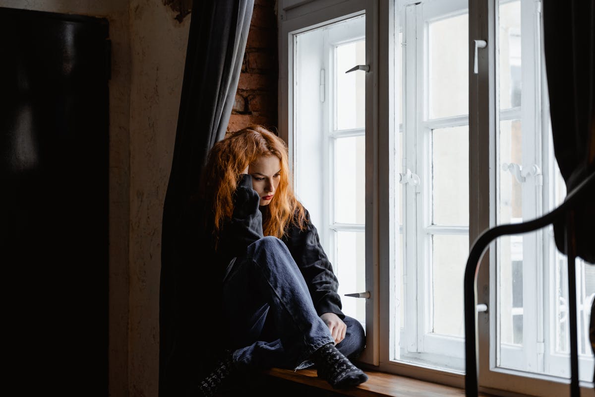 donna capelli rossi che pensa su davanzale finestra