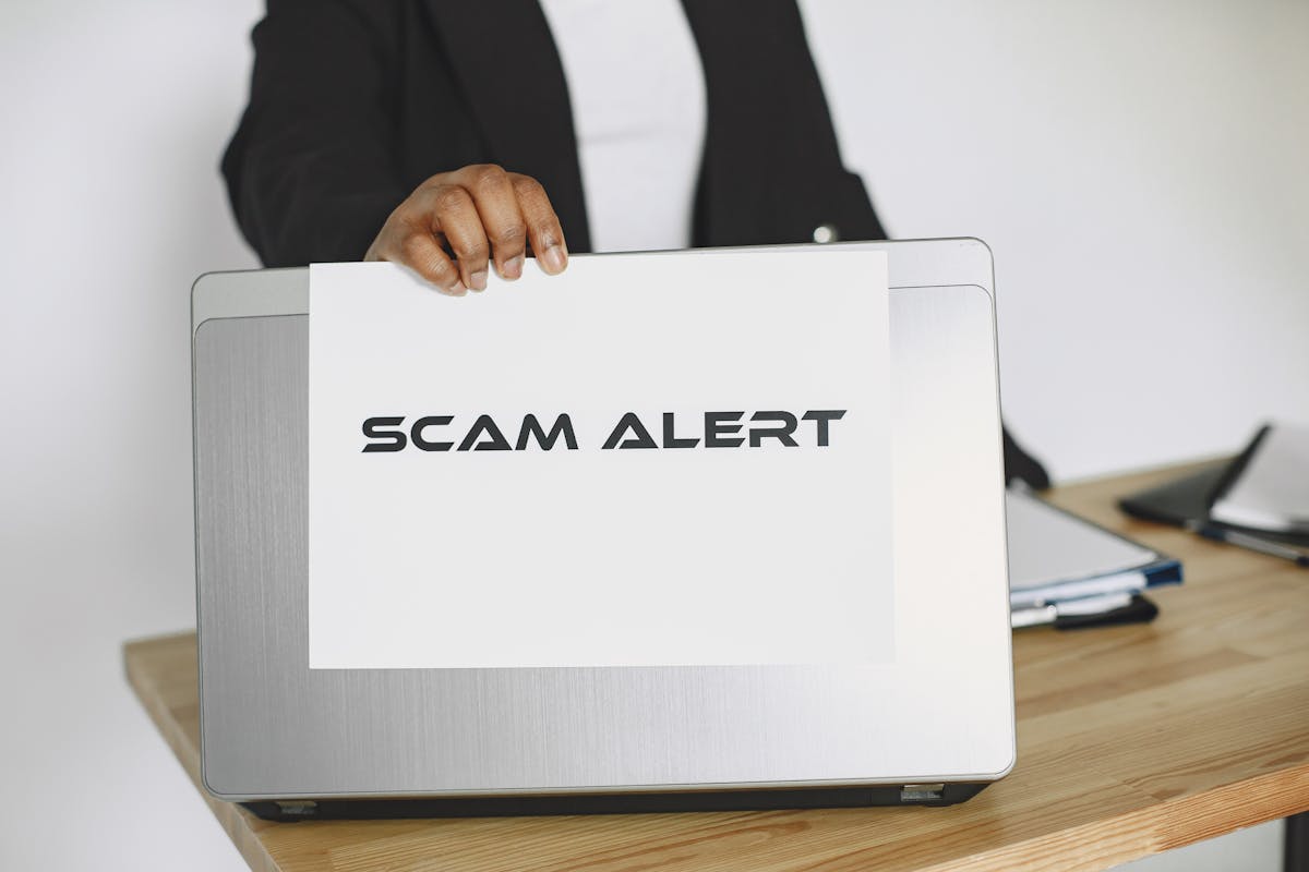 Computer con foglio con su scritto SCAM ALERT
