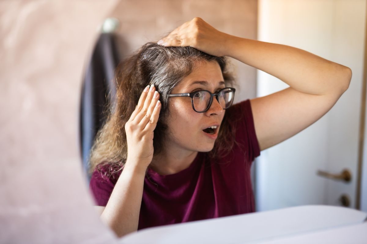 persona che si guarda allo specchio con capelli bianchi