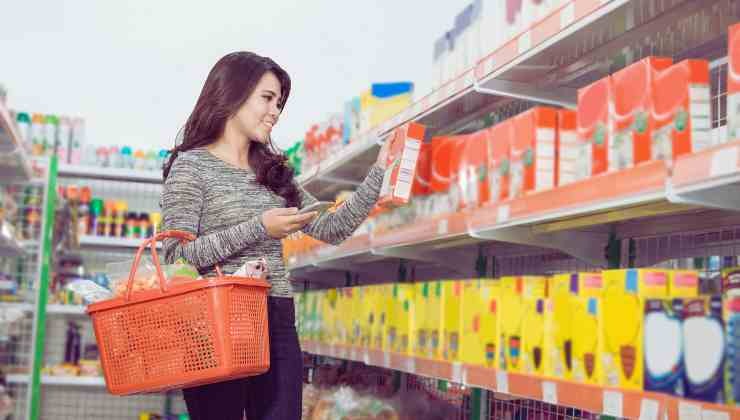 donna che guarda prodotti scaffali supermercato