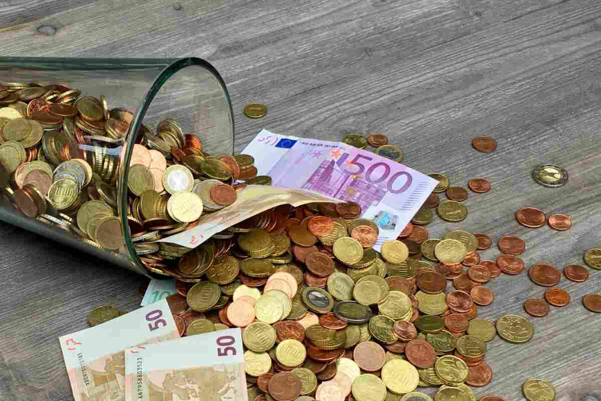 Monete e banconote che cadono da un bicchiere