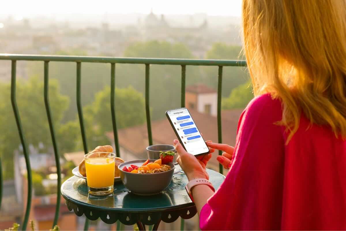 Ragazza al cellulare davanti tavolo colazione