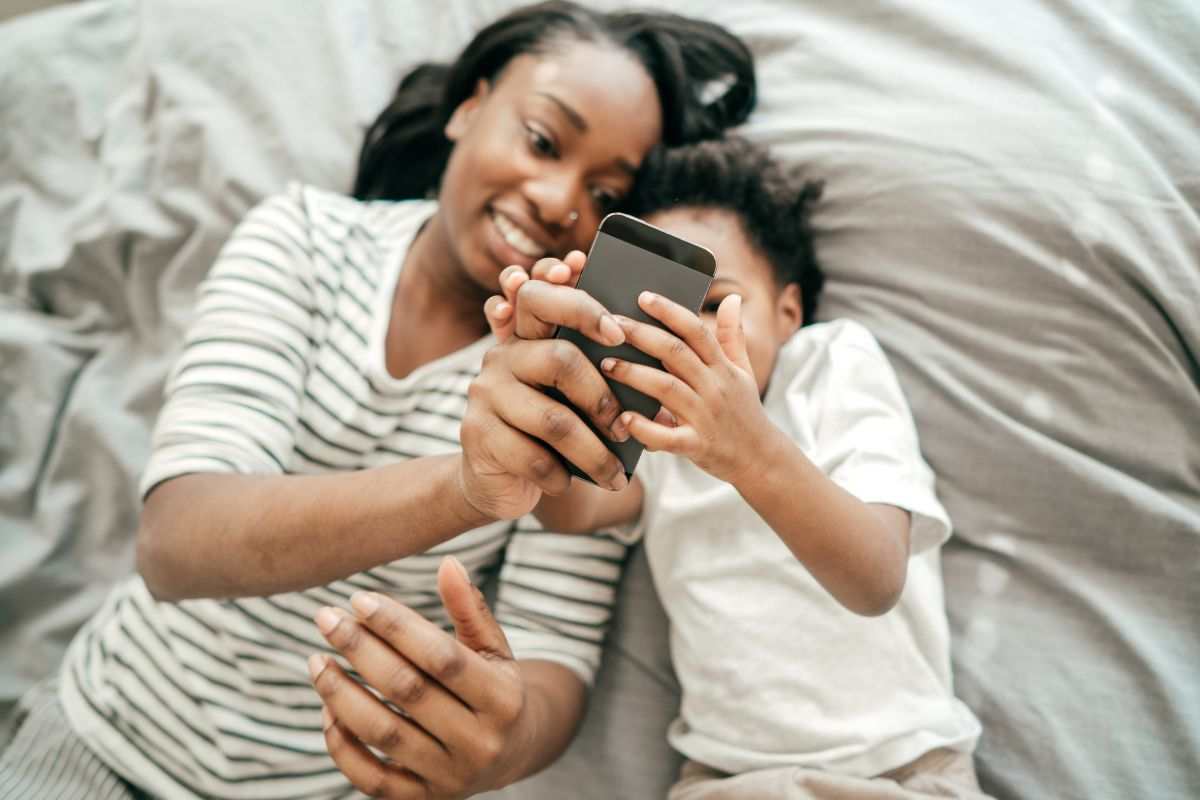 mamma e figlio sul letto che guardano smartphone