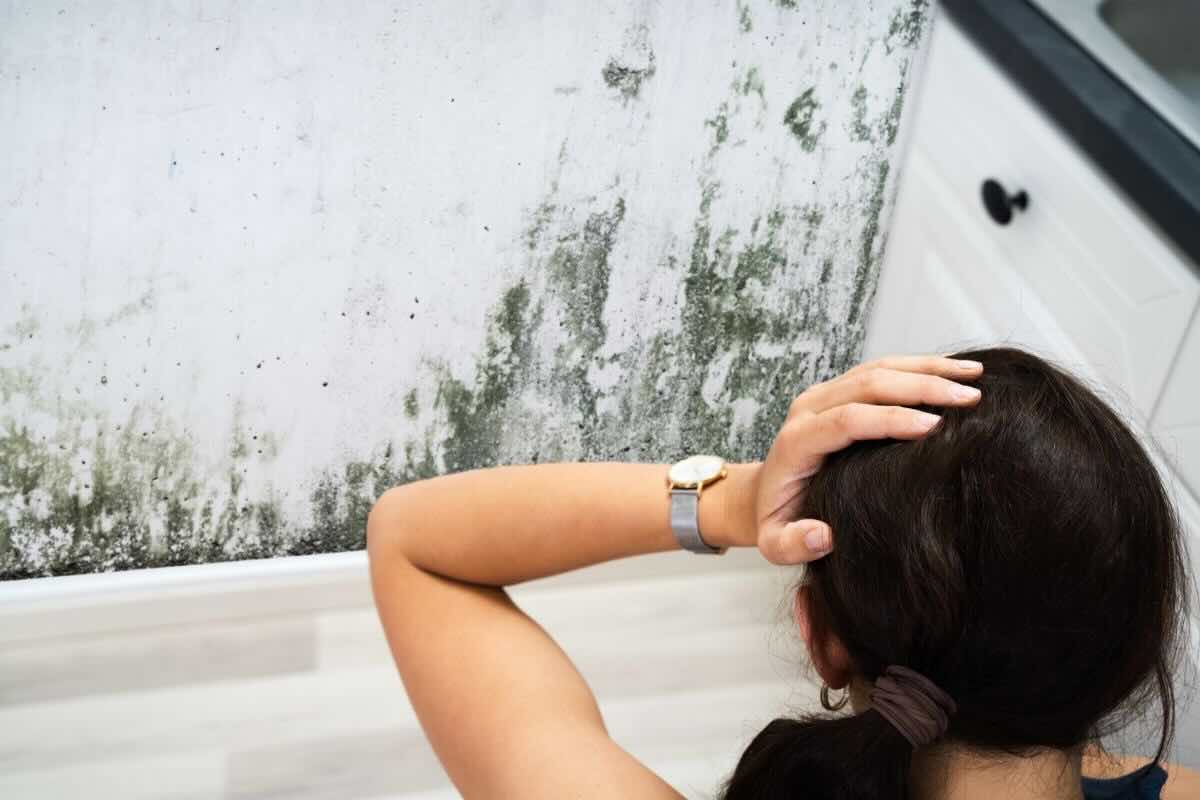Donna mani nei capelli guarda muffa sulla parete