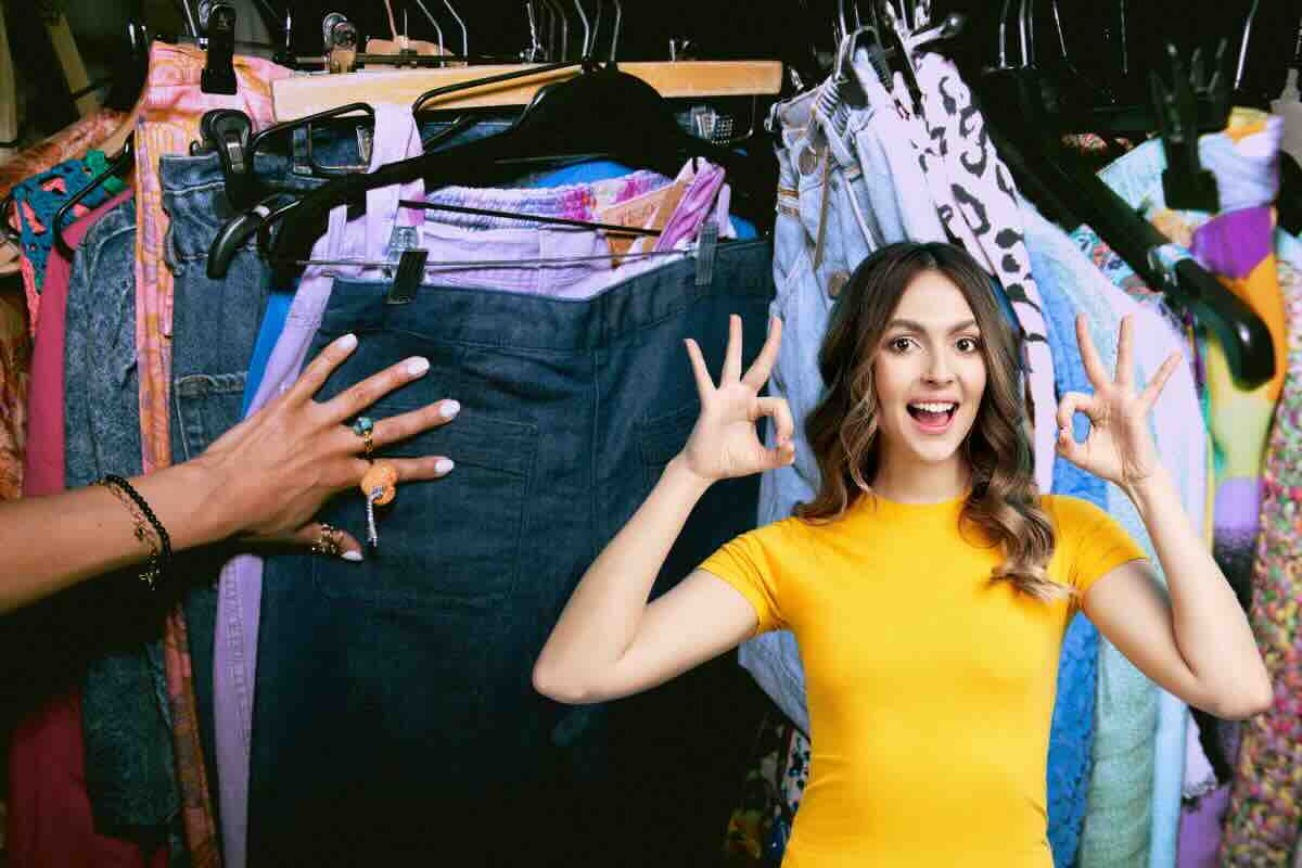 abiti vintage appesi e donna che fa ok con le mani