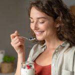 Ragazza mangia yogurt con frutti di bosco