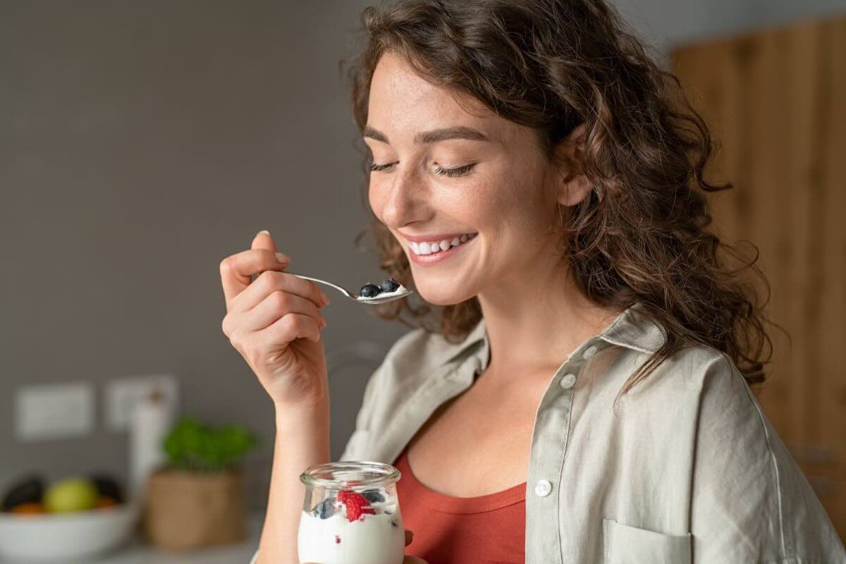 Ragazza mangia yogurt con frutti di bosco