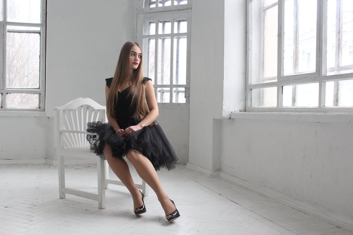 donna con vestito e tacchi seduta in stanza bianca